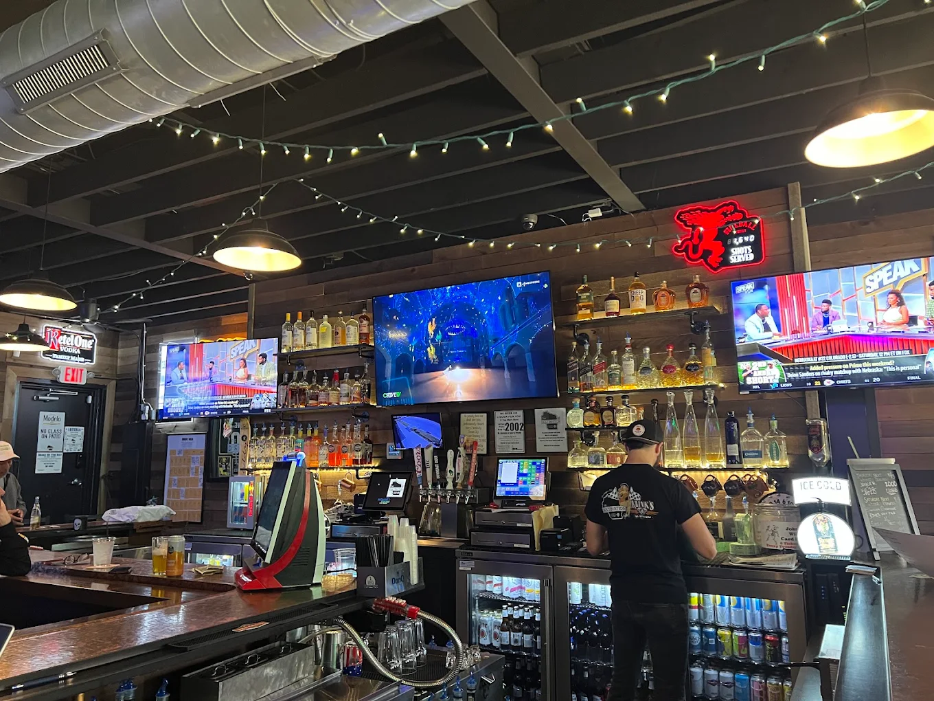Inside The Destination: wood-panelled bar with sports on multiple TVs and string lights overhead